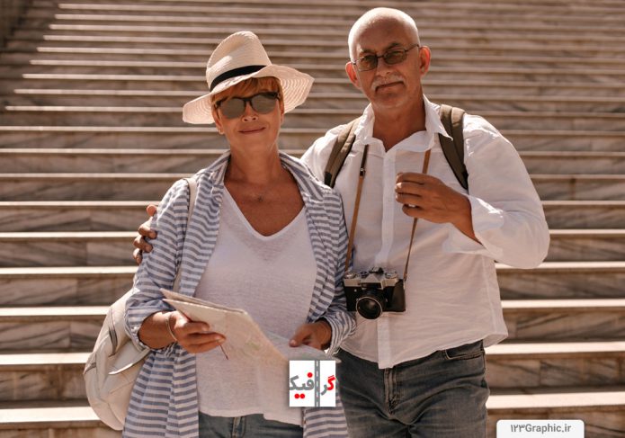 عکس-پیر-مرد-عکاس-با-دوربین-عکاسی-در-گردن-و-همسرش-در-حال-گردشگری